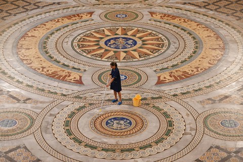 Salah satu pekerja membersihkan lantai Minton Tile asli di St George's Hall di Liverpool, Inggris pada Senin (31/7/2023). Foto: Paul Ellis/AFP