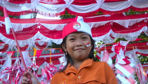 Seorang anak yang mengenakan aksesoris dengan latar bendera merah putih di kawasan Jalan Merdeka Palembang jelang perayaan kemerdekaan, Sabtu (5/8) Foto: ary priyanto/urban id