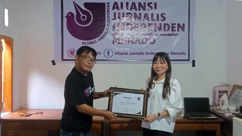 Ketua AJI Manado, Fransiskus Marcelino Talokon menyerahkan piagam penghargaan untuk Psikolog Klinis, Hanna Monareh M Psi, pada peringatan HUT ke-29 AJI.