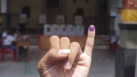Seseorang menunjukkan jari kelingkingnya yang sudah dicelupkan ke tinta ungu sebagai tanda bahwa ia telah secara sah memberikan suara dalam pemilu. Sumber: iSctock.com.