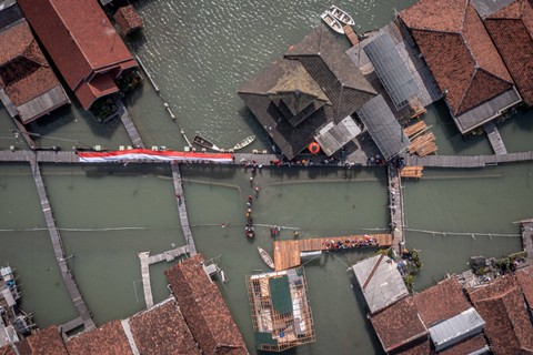 Foto udara upacara bendera di perkampungan yang terendam limpasan air laut ke daratan atau banjir rob di Dusun Timbulsloko, Desa Timbulsloko, Kecamatan Sayung, Kabupaten Demak, Jawa Tengah, Kamis (17/8/2023). Foto: Aji Styawan/Antara Foto