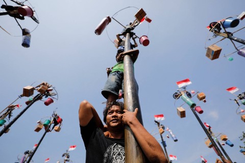 Para peserta mencoba mencapai puncak tiang yang sudah dilumuri minyak untuk mengumpulkan hadiah, dalam kompetisi "Panjat Pinang", yang diadakan untuk merayakan HUT ke-78 RI, di Pantai Ancol di Jakarta, Kamis (17/8/2023). Foto: Willy Kurniawan/REUTERS