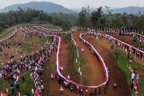 Sejumlah warga membentangkan bendera bertemakan "Langkaplancar Berkibar Untuk Indonesia" di Sirkuit Serdadu, Kecamatan Langkaplancar, Kabupaten Pangandaran, Jawa Barat, Sabtu (19/8/2023). Foto: Adeng Bustomi/ANTARA FOTO