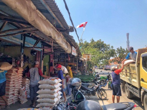 Pekerja grosir beras saat menurunkan dan memanggul beras dari truk beras di Pasar Tradisional Kabupaten Indramayu. (5/9/2023). Foto: kumparan