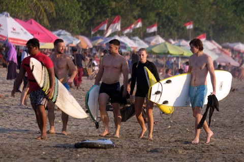 Sejumlah wisatawan membawa papan selancar saat berlibur di Pantai Kuta, Badung, Bali, Senin (25/9/2023). Foto: Nyoman Hendra Wibowo/Antara Foto