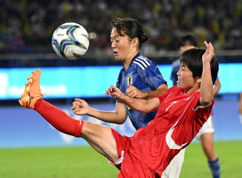Sung Hyang Sim (kanan) dari Korea Utara menendang bola saat Wakaba Goto dari Jepang menonton pertandingan perebutan medali emas sepak bola putri antara Jepang dan Korea Utara pada Asian Games 2022 di Hangzhou pada Jumat (6/10/2023). Foto: Jung Yeon-je / AFP