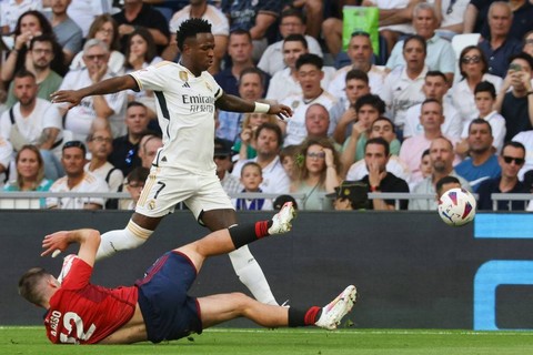 Vinicius Junior berduel dengan Jesus Areso Blanco dalam pertandingan Liga Spanyol 2023/24 antara Real madrid vs Osasuna di Stadion Santiago Bernabeu, Madrid, Spanyol, pada Sabtu (7/10). Foto: Pierre-Philippe Marcou/AFP