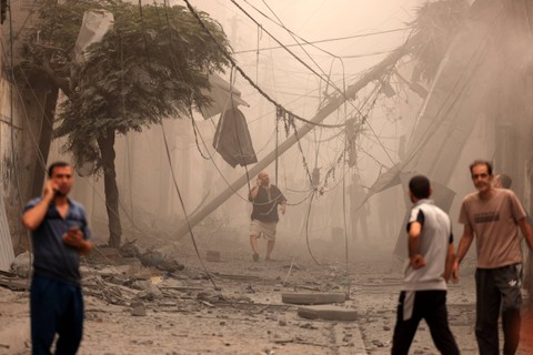 Warga Palestina memeriksa kehancuran di lingkungan yang rusak parah akibat serangan udara Israel di kamp pengungsi Shati Kota Gaza, Senin (9/10/2023).  Foto: MAHMUD HAMS / AFP