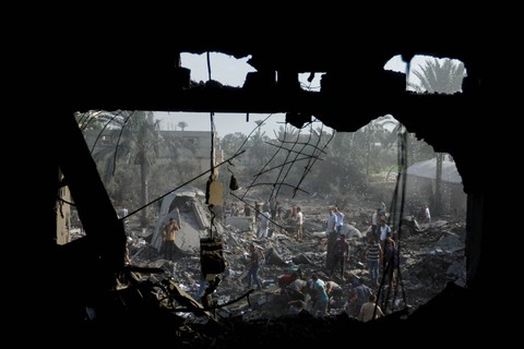 Warga Palestina berkumpul di puing-puing pasca serangan Israel, di Khan Younis di selatan Jalur Gaza, Rabu (11/10/2023). Foto: Ibraheem Abu Mustafa/REUTERS