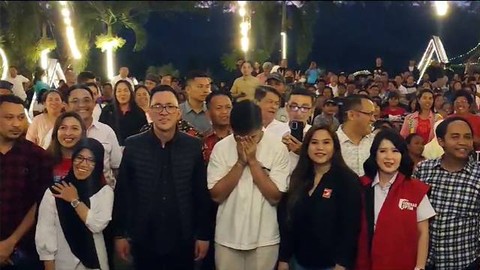 Kaesang Pangarep tertunduk dan menutup wajahnya dengan kedua tangan, saat MC meminta agar peserta yang berfoto bersama mengepalkan tangan dan menerikkan nama Jokowi.