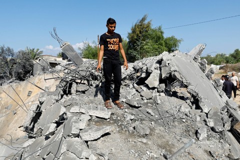 Warga Palestina berdiri di lokasi serangan Israel di sebuah rumah di Khan Younis di Jalur Gaza selatan, Kamis (19/10/2023).  Foto: Ibraheem Abu Mustafa/REUTERS
