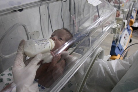 Seorang petugas medis Palestina memberi makan bayi di inkubator rumah sakit al-Quds di selatan Kota Gaza pada 15 Januari 2009. Foto: Mehdi Fedouach/AFP
