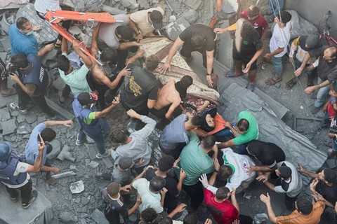 Warga Palestina menyelamatkan seorang wanita di lokasi serangan Israel terhadap rumah-rumah, di Khan Younis di Jalur Gaza selatan, Kamis (26/10/2023). Foto: Fadi Shana/REUTERS