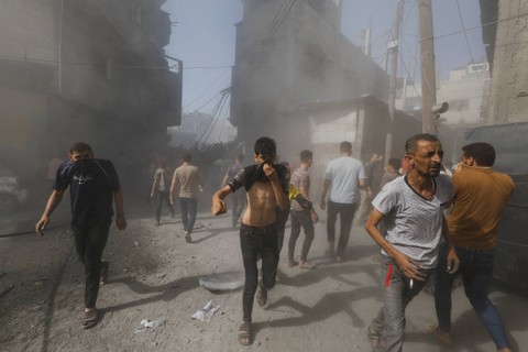 Warga Palestina berlarian di lokasi serangan Israel terhadap rumah-rumah, di Khan Younis di Jalur Gaza selatan, Kamis (26/10/2023). Foto: Mohammed Salem/REUTERS