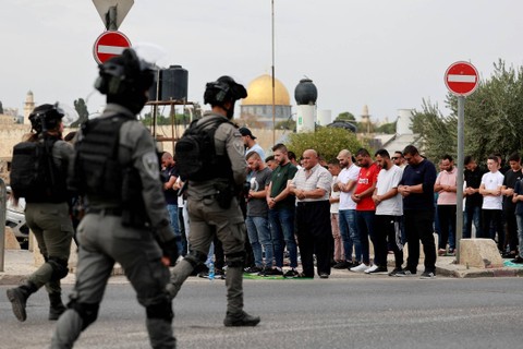 Polisi Israel berjalan saat warga Muslim Palestina melaksanakan salat Jumat di jalan di luar Kota Tua Yerusalem, di Yerusalem, Jumat (27/10/2023). Foto: Ammar Awad/REUTERS