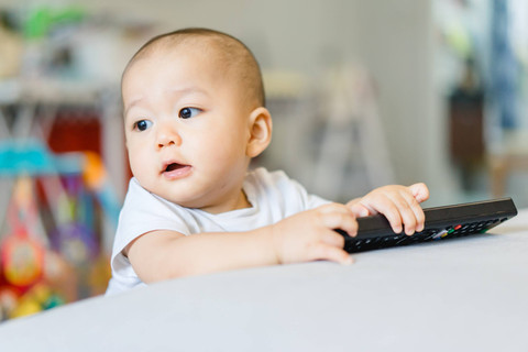 Bayi main remot TV. Foto: Shutterstock