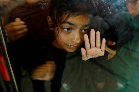 Seorang anak melihat melalui kaca, ketika warga Palestina dengan kewarganegaraan ganda menunggu di perbatasan Rafah dengan Mesir, dengan harapan mendapatkan izin meninggalkan Gaza. Foto: Ibraheem Abu Mustafa/Reuters