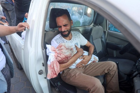 Seorang pria Palestina membawa jenazah putranya Ahmed al-Badrasawi yang tewas dalam serangan Israel, di rumah sakit Shuhada Al-Aqsa di Jalur Gaza tengah 31 Oktober 2023. Foto: Ahmed Zakot/Reuters