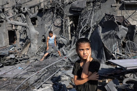 Seorang gadis melihat ketika dia berdiri di dekat reruntuhan di luar sebuah gedung yang terkena pemboman Israel di Rafah di Jalur Gaza selatan pada 31 Oktober 2023. Foto: Said Khatib/AFP