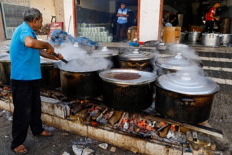 Warga Palestina memasak dengan kayu bakar di Khan Younis, Jalur Gaza selatan, Minggu (5/11/2023). Foto: Ibraheem Abu Mustafa/REUTERS