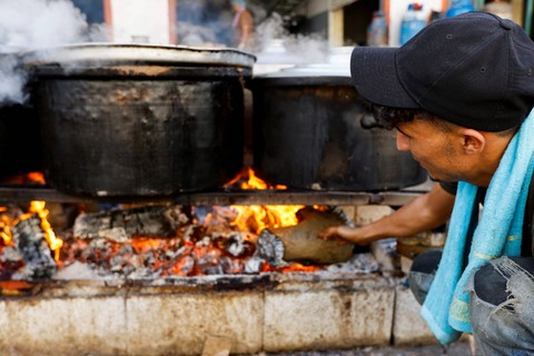 Warga Palestina memasak dengan kayu bakar di Khan Younis, Jalur Gaza selatan, Minggu (5/11/2023). Foto: Ibraheem Abu Mustafa/REUTERS