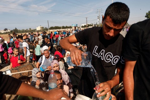Orang-orang mengumpulkan air sementara warga Palestina yang melarikan diri dari Gaza utara bergerak ke selatan, setelah pasukan Israel mendekat ke daerah kantong tersebut, di Jalur Gaza tengah, Jumat (10/11/2023). Foto: Ibraheem Abu Mustafa/REUTERS
