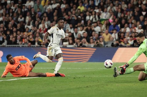 Vinicius Junior (tengah) coba mencetak gol dalam pertandingan Liga Spanyol 2023/24 antara Real Madrid vs Valencia di Stadion Santiago Bernabeu, Madrid, Spanyol, pada Minggu (12/11). Foto: Thomas Coex/AFP