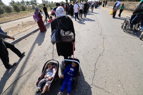 Keluarga warga Palestina yang meninggalkan Kota Gaza dan bagian lain Gaza utara menuju wilayah selatan, berjalan di sepanjang jalan pada Jumat (10/11/2023). Foto: Mahmud Hams/AFP