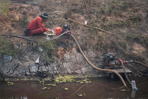 Makan di Pinggir Kanal - Personel Manggala Agni Daops Banyuasin menyantap makan siang di pinggir kanal saat melakukan pemadaman kebakaran hutan dan lahan. Foto: Nova Wahyudi/Antara Foto