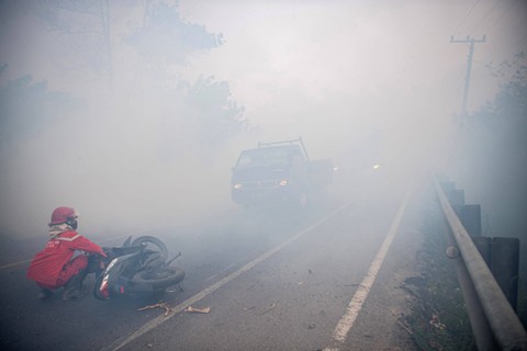 Membantu Warga - Personel Manggala Agni Daops Banyuasin menolong pengendara sepeda motor yang mengalami kecelakaan akibat kabut asap di Jalan Lintas Palembang-Indralaya di Desa Sungai Rambutan, Indralaya Utara, Ogan Ilir (OI). Foto: Nova Wahyudi/Antara Foto