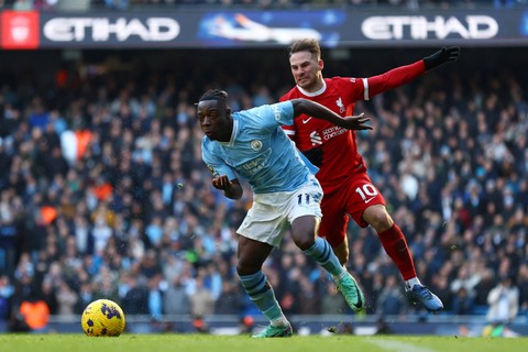 Pemain Manchester City Jeremy Doku berebut bola dengan pemain Liverpool Alexis Mac Allister pada pertandingan Liga Inggris di Stadion Etihad, Manchester, Inggris, Sabtu (25/11/2023). Foto: Carl Recine/REUTERS