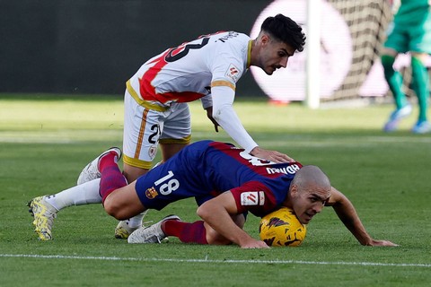 Pemain FC Barcelona Oriol Romeu berebut bola dengan pemain Rayo Vallecano Oscar Valentin pada pertandingan Liga Spanyol di Stadion Campo de Futbol de Vallecas, Madrid, Spanyol, Sabtu (25/11/2023). Foto: OSCAR DEL POZO / AFP