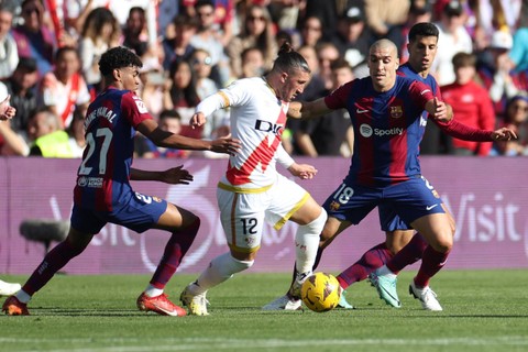 Pemain FC Barcelona Lamine Yamal dan Oriol Romeu berebut bola dengan pemain Rayo Vallecano Alfonso Espino pada pertandingan Liga Spanyol di Stadion Campo de Futbol de Vallecas, Madrid, Spanyol, Sabtu (25/11/2023). Foto: Isabel Infantes/REUTERS