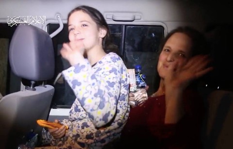 Warga Israel yang dibebaskan melambaikan tangan dan tersenyum kepada pejuang Brigade Al-Qassam, sayap militer Hamas, Minggu (26/11/2023) (Brigade Al-Qassam) Foto: Dok. Istimewa