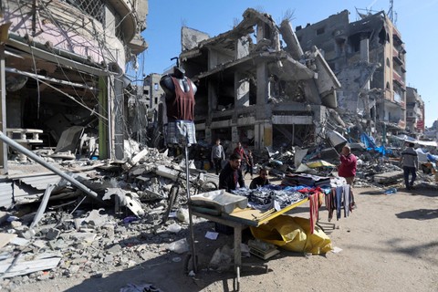 Warga Palestina berbelanja di pasar terbuka dekat reruntuhan rumah dan bangunan yang hancur akibat serangan Israel di kamp pengungsi Nuseirat di Jalur Gaza tengah, Kamis (30/11/2023). Foto: Ibraheem Abu Mustafa/REUTERS