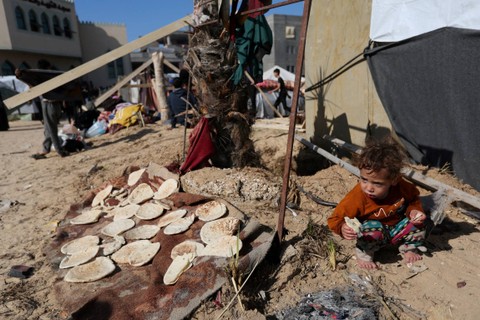 Seorang anak makan di luar tenda, saat warga Palestina yang mengungsi, di sebuah kamp di Rafah, di Jalur Gaza selatan, Rabu (6/12/2023). Foto: Ibraheem Abu Mustafa/REUTERS