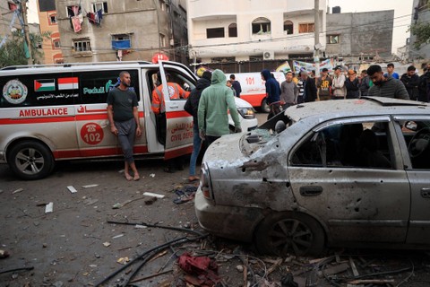 Warga Palestina berkumpul di dekat ambulans setelah pemboman Israel di Rafah, di Jalur Gaza selatan pada Selasa (12/12/2023). Foto: Said Khatib/AFP