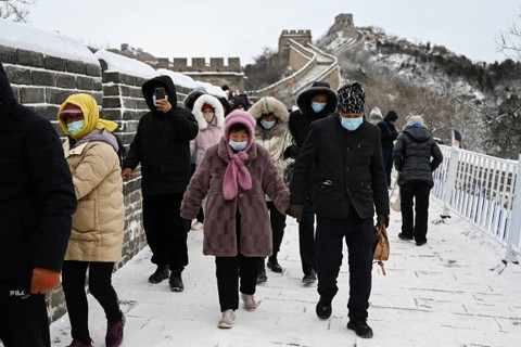 Orang-orang berjalan di bagian es Tembok Besar China di Badaling, utara Beijing, setelah hujan salju semalaman, Jumat (15/12/2023). Foto: Greg Baker/AFP