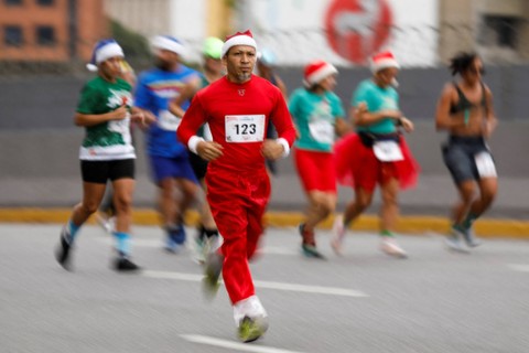 Seorang pelari bertopi Natal mengikuti lomba lari 10 kilometer Santa Run, di Caracas, Venezuela, Minggu (17/12/2023). Foto: Leonardo Fernandez Viloria/REUTERS