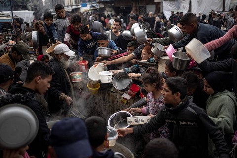 Warga Palestina mengantri untuk mendapatkan makanan gratis di Rafah, Jalur Gaza, Kamis (21/12/2023). Foto: Fatima Shbair/AP Photo