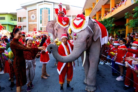 Guru dan siswa menunggu hadiah dari gajah yang mengenakan kostum Sinterklas menjelang perayaan Natal di sebuah sekolah dasar, di Ayutthaya, Thailand, Jumat (22/12/2023). Foto: Artorn Pookasook/REUTERS