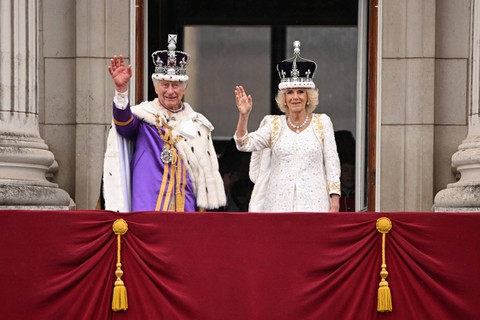 Raja Charles III dan Ratu Camilla melambaikan tangan usai penobatan di Istana Buckingham, Inggris, pada 6 Mei 2023. Foto: Oli SCARFF / AFP
