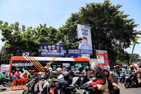 Melintas di dekat APK: Sejumlah kendaraan melintas di samping alat peraga kampanye (APK) Pemilu 2024 yang terpasang di Kalibata, Jakarta Selatan. Foto: Iqbal Firdaus/kumparan