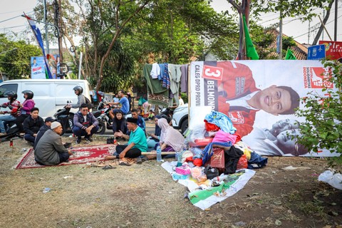 Kumpul di dekat APK: Warga duduk di dekat alat peraga kampanye (APK) Pemilu 2024 yang terpasang di Manggarai, Jakarta. Foto: Iqbal Firdaus/kumparan