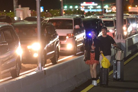 Calon penumpang pesawat berjalan di Jalan Tol Bali Mandara setelah mobil yang ditumpanginya terjebak kemacetan saat akan menuju ke Bandara Internasional I Gusti Ngurah Rai di Badung, Bali, Jumat (29/12/2023). Foto: Fikri Yusuf/ANTARA FOTO