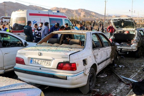 Orang-orang berkumpul dekat mobil yang hancur di lokasi ledakan saat upacara yang diadakan untuk memperingati kematian mendiang Jenderal Iran Qassem Soleimani, di Kerman, Iran, Rabu (3/1/2024). Foto: WANA via REUTERS