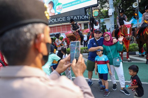 Sejumlah warga berfoto dengan Polisi Berkuda dari Detasemen Turangga Direktorat Polisi Satwa Polri saat Car Free Day (CFD) atau Hari Bebas Kendaraan Bermotor di kawasan Bundaran HI, Jakarta, Minggu (7/1). Foto: Iqbal Firdaus/kumparan