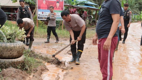 Kapolres Sekadau mencangkul membuat saluran air saat gotong royong bersama warga memperbaiki jalan rusak di Lamau. Foto: Dok. Polres Sekadau