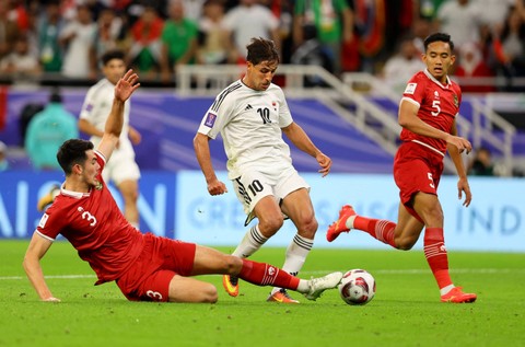Mohanad Ali dari Irak duel dengan Elkan Baggott dari Indonesia saat pertandingan Piala Asia AFC Grup D di Stadion Ahmad bin Ali, Al Rayyan, Qatar. Foto: Ibraheem Al Omari/Reuters