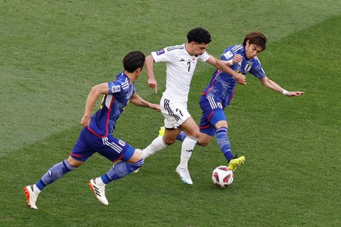 Pemain Timnas Irak Youssef Amyn beraksi bersama pemain Timnas Jepang Junya Ito pada Piala Asia 2023, di Education City Stadium, Al Rayyan, Qatar, Jumat (19/1/2024). Foto: Thaier Al-Sudani/REUTERS